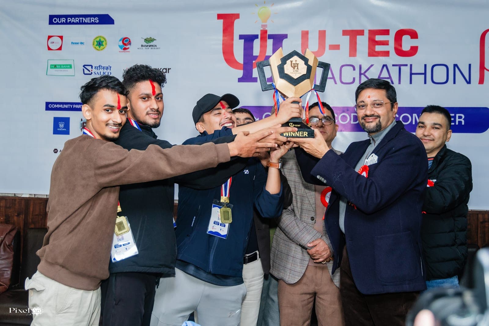Hackathon winners lifting the trophy on stage with guests